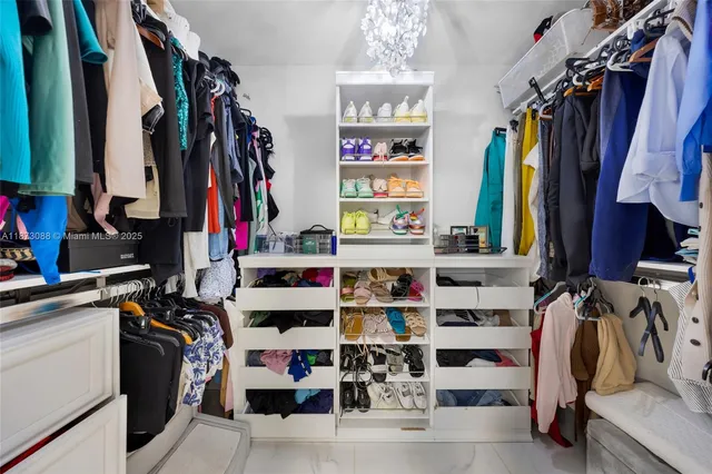 a view of walk in closet with clothes and shoes
