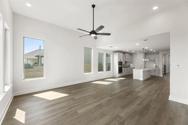 a view of an empty room with a kitchen and wooden floor