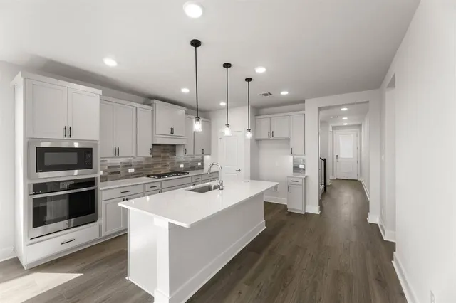 a kitchen with a sink stainless steel appliances and wooden floor