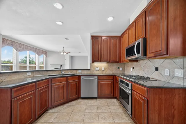 a kitchen with stainless steel appliances granite countertop wooden cabinets a sink and dishwasher a oven with wooden cabinets