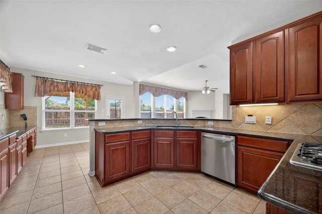 a kitchen with a sink stainless steel appliances wooden cabinets and a window