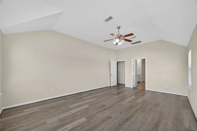 an empty room with a ceiling fan and wooden floor