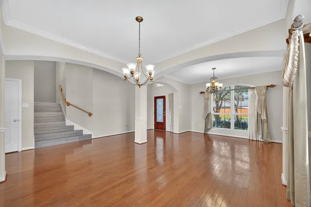 a view of an empty room with wooden floor and a chandelier