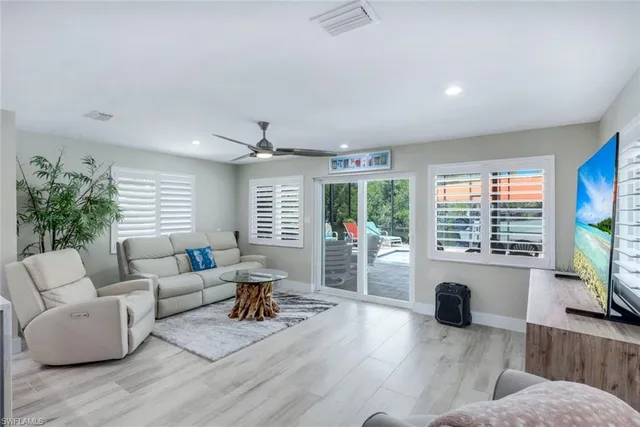 a living room with furniture a large window and wooden floor