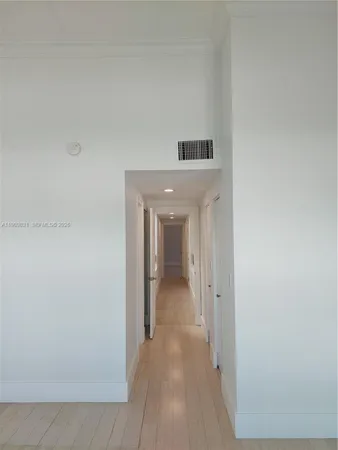 a view of an empty room with wooden floor and a ceiling fan