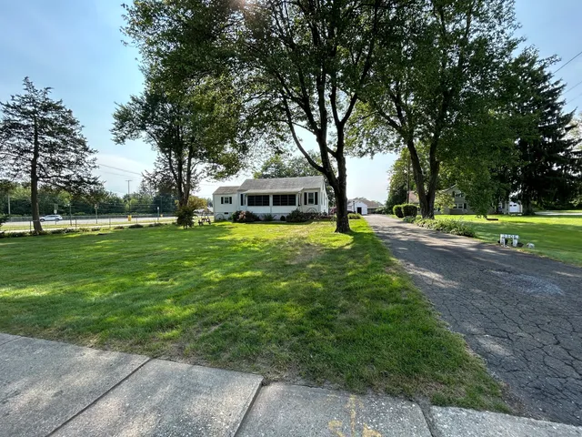 a view of a house with a big yard and large trees