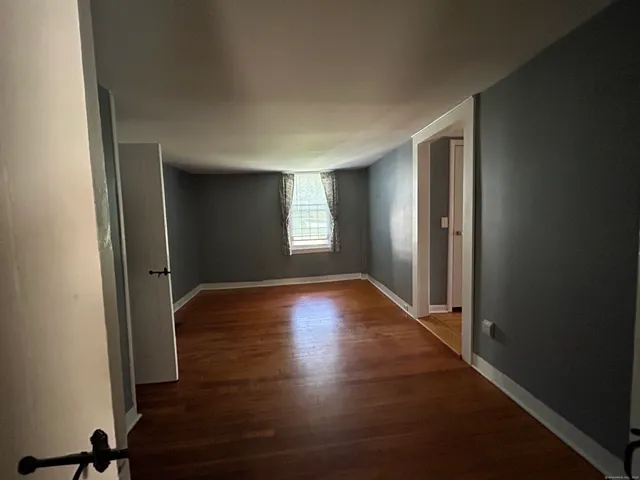 a view of empty room with window and wooden floor