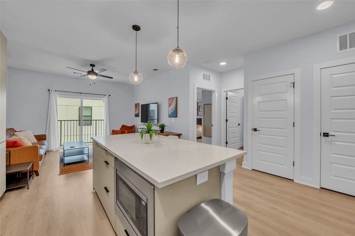 2500 Longview Street, Unit 217 Austin, TX 78705 - Photo 35 of 35 Kitchen with stainless steel microwave, light countertops, hanging light fixtures, light wood-type flooring, and open floor plan