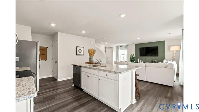 a living room with stainless steel appliances kitchen island granite countertop a refrigerator and a flat screen tv
