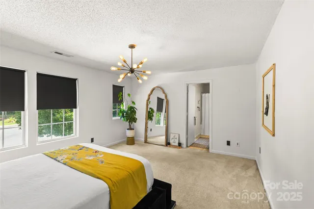 a spacious bedroom with a bed a dresser and windows