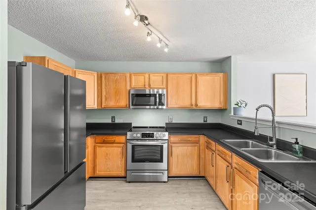 a kitchen with stainless steel appliances granite countertop a sink stove and refrigerator
