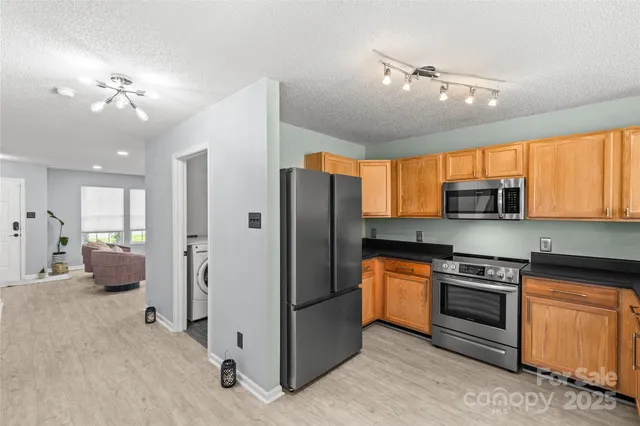 a kitchen with stainless steel appliances granite countertop a refrigerator oven stove a sink dishwasher and white cabinets with wooden floor