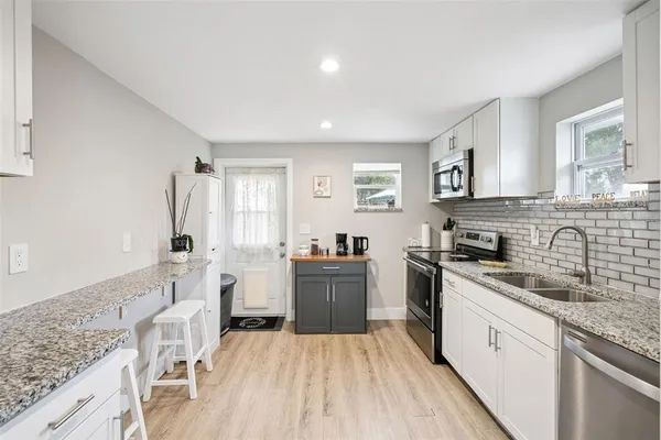a kitchen with a sink stove cabinets and wooden floor