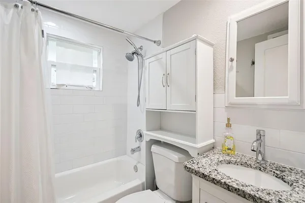 a bathroom with a granite countertop tub sink and mirror