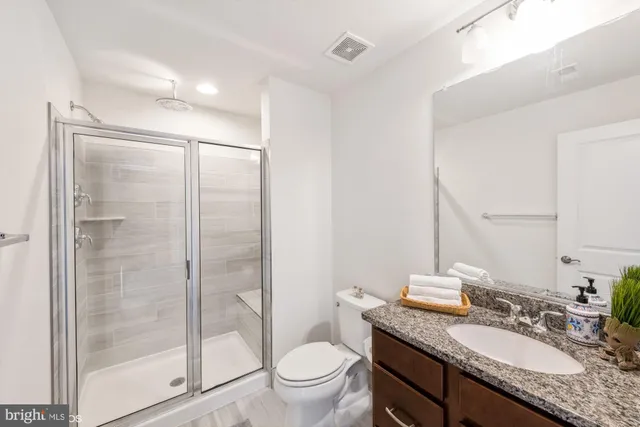 a bathroom with a granite countertop sink toilet and shower