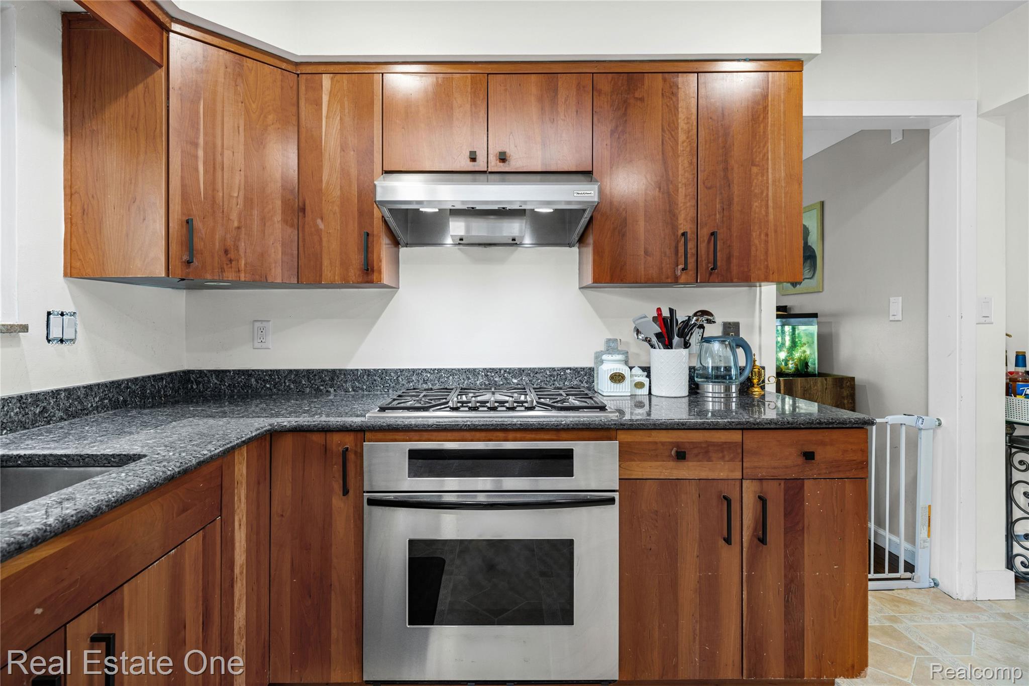 2810 Walbridge Drive Rochester, MI 48307 - Photo 17 of 58 Thoughtfully designed kitchen featuring wood cabinetry, dark speckled countertops, stainless steel gas range, integrated oven, and a stainless steel range hood