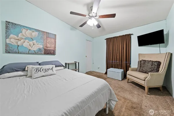 a bedroom with a bed a couch and a flat screen tv