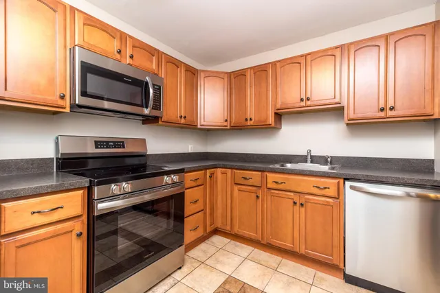 a kitchen with stainless steel appliances granite countertop a stove top oven a sink dishwasher and a microwave oven on the blue kitchen countertops