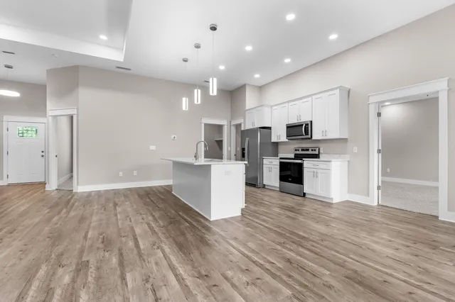 a view of kitchen with microwave a refrigerator and white cabinets