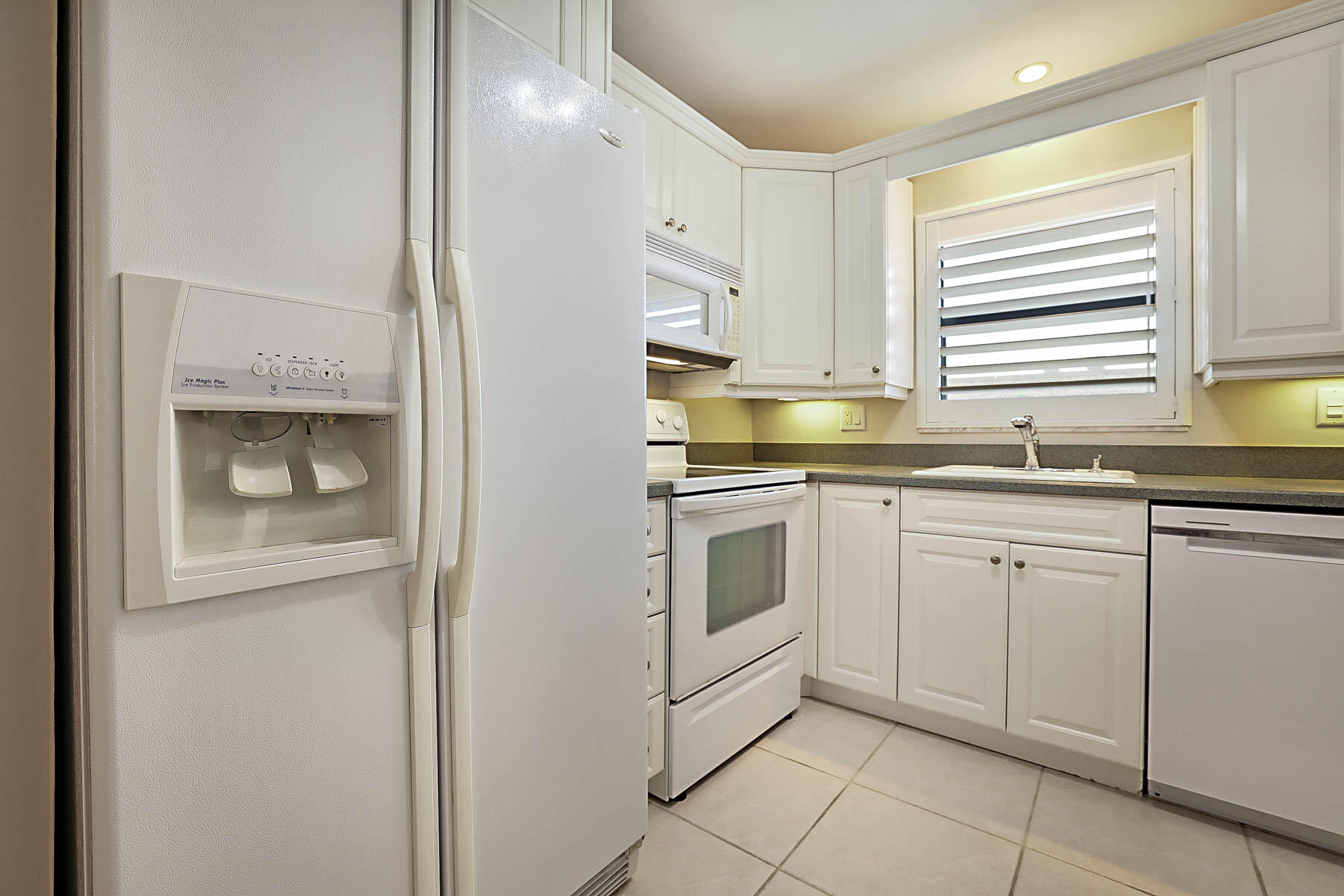 755 Saturn Street, Unit F203 Jupiter, FL 33477 - Photo 21 of 36 a kitchen with white cabinets and white appliances