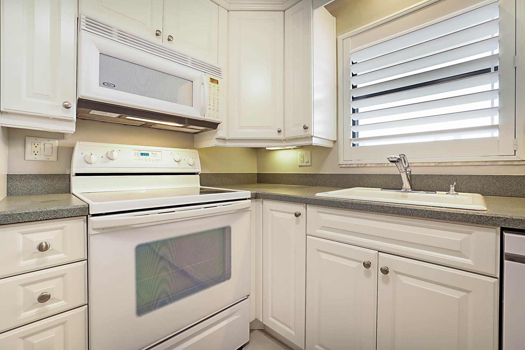 755 Saturn Street, Unit F203 Jupiter, FL 33477 - Photo 22 of 36 a kitchen with granite countertop white cabinets and white appliances