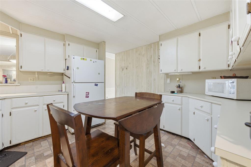 8045 Indian Trail Road Weeki Wachee, FL 34613 - Photo 9 of 49 a kitchen with stainless steel appliances a white table chairs and a refrigerator