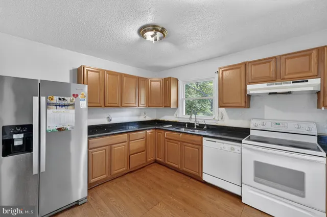 a kitchen with granite countertop a sink stainless steel appliances and cabinets