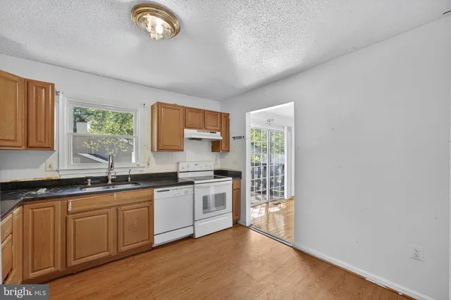 a kitchen with stainless steel appliances granite countertop a sink and a stove next to a window