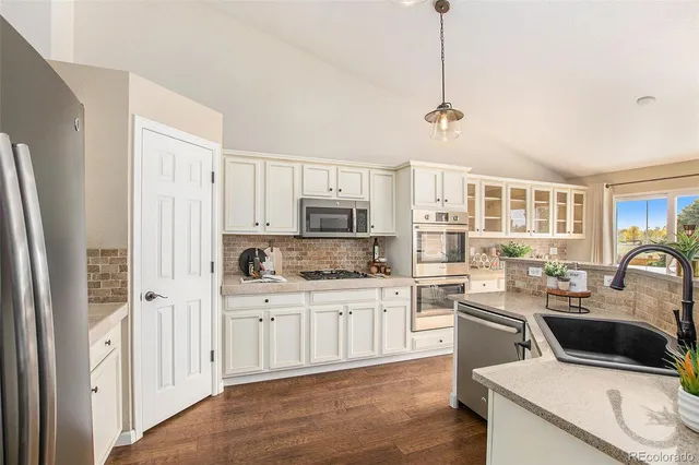 a kitchen with a sink a stove a refrigerator cabinets and living room view