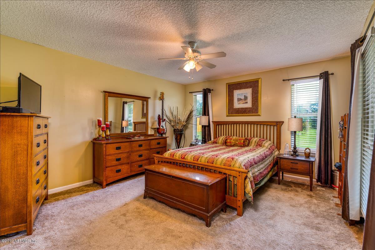 1372 Blackmon Road Green Cove Springs, FL 32043 - Photo 19 of 26 a bedroom with a bed and a chandelier