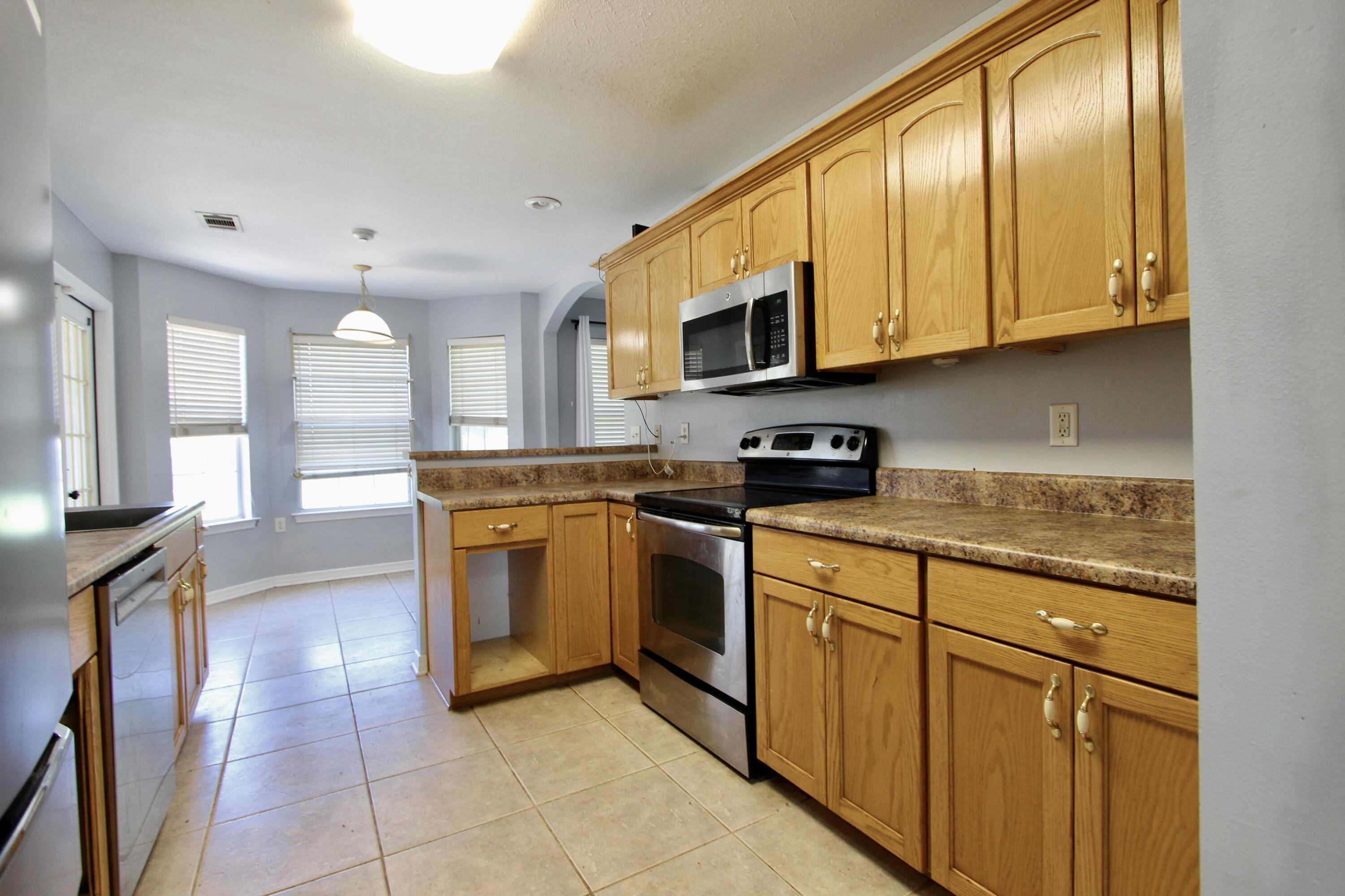 6064 Buckward Road Baker, FL 32531 - Photo 15 of 34 a kitchen with stainless steel appliances granite countertop a stove a sink and a microwave