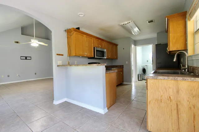 a view of an empty room with a window and chandelier fan