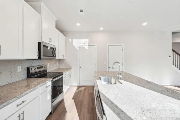 a large kitchen with stainless steel appliances granite countertop a lot of counter space and wooden floor