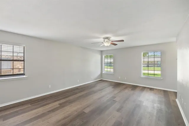 a view of an empty room with a window and wooden floor