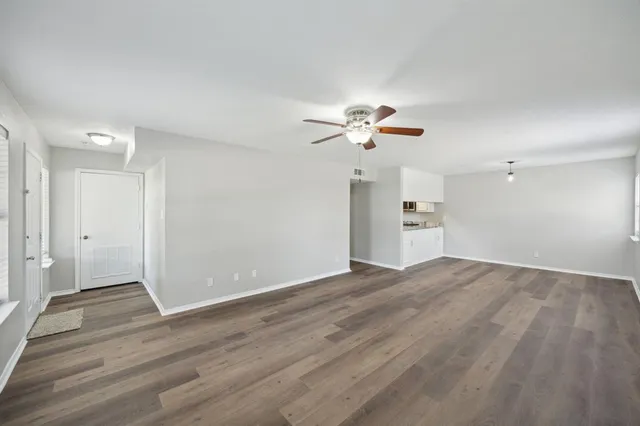 an empty room with wooden floor and chandelier fan