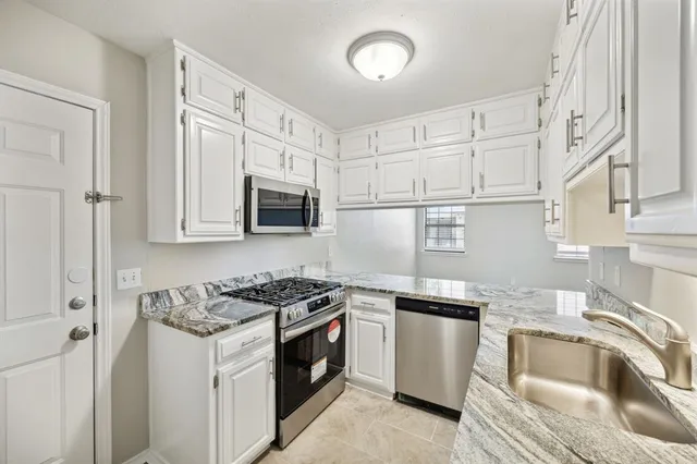 a kitchen with granite countertop a sink stove and refrigerator