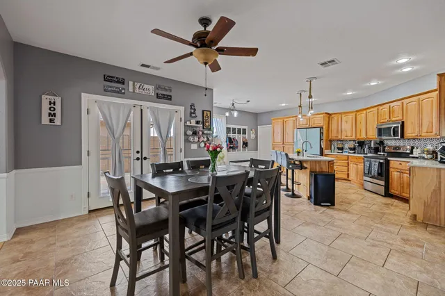 a kitchen with stainless steel appliances kitchen island granite countertop a table chairs and a refrigerator