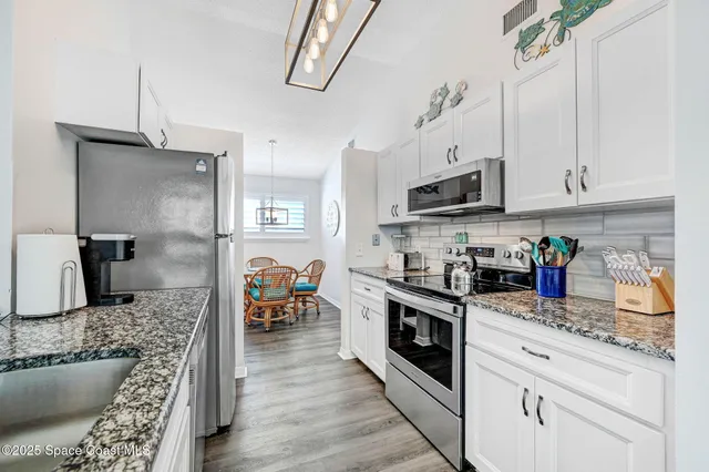 a kitchen with stainless steel appliances a refrigerator and a wooden floor