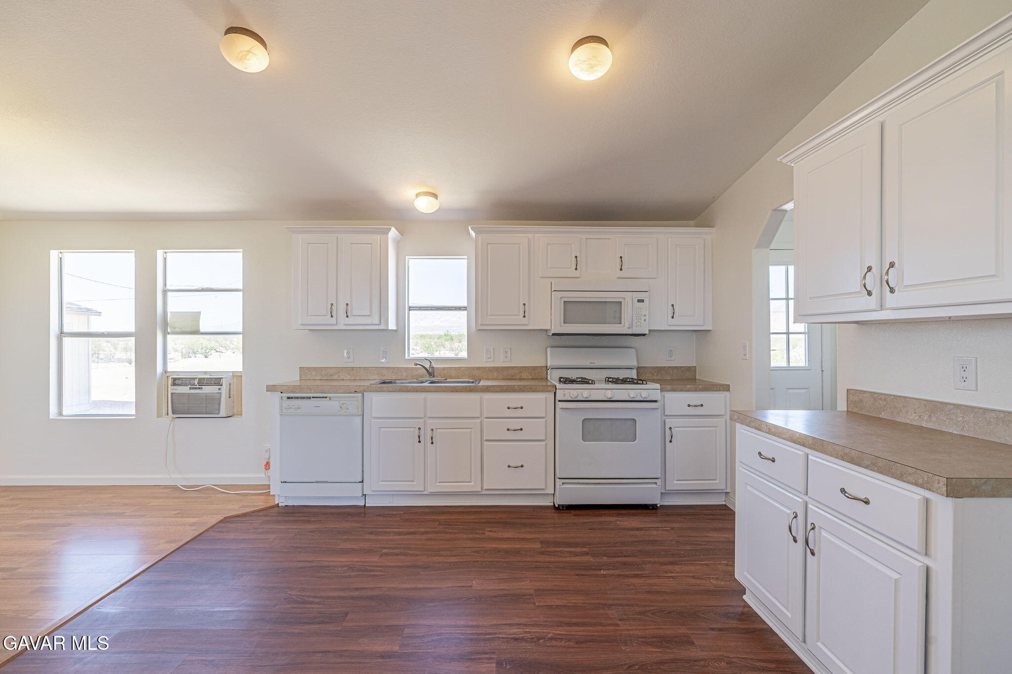 26321 Olanche Street Mojave, CA 93501 - Photo 13 of 40 a large kitchen with granite countertop a stove top oven a sink a dishwasher and white cabinets with wooden floor