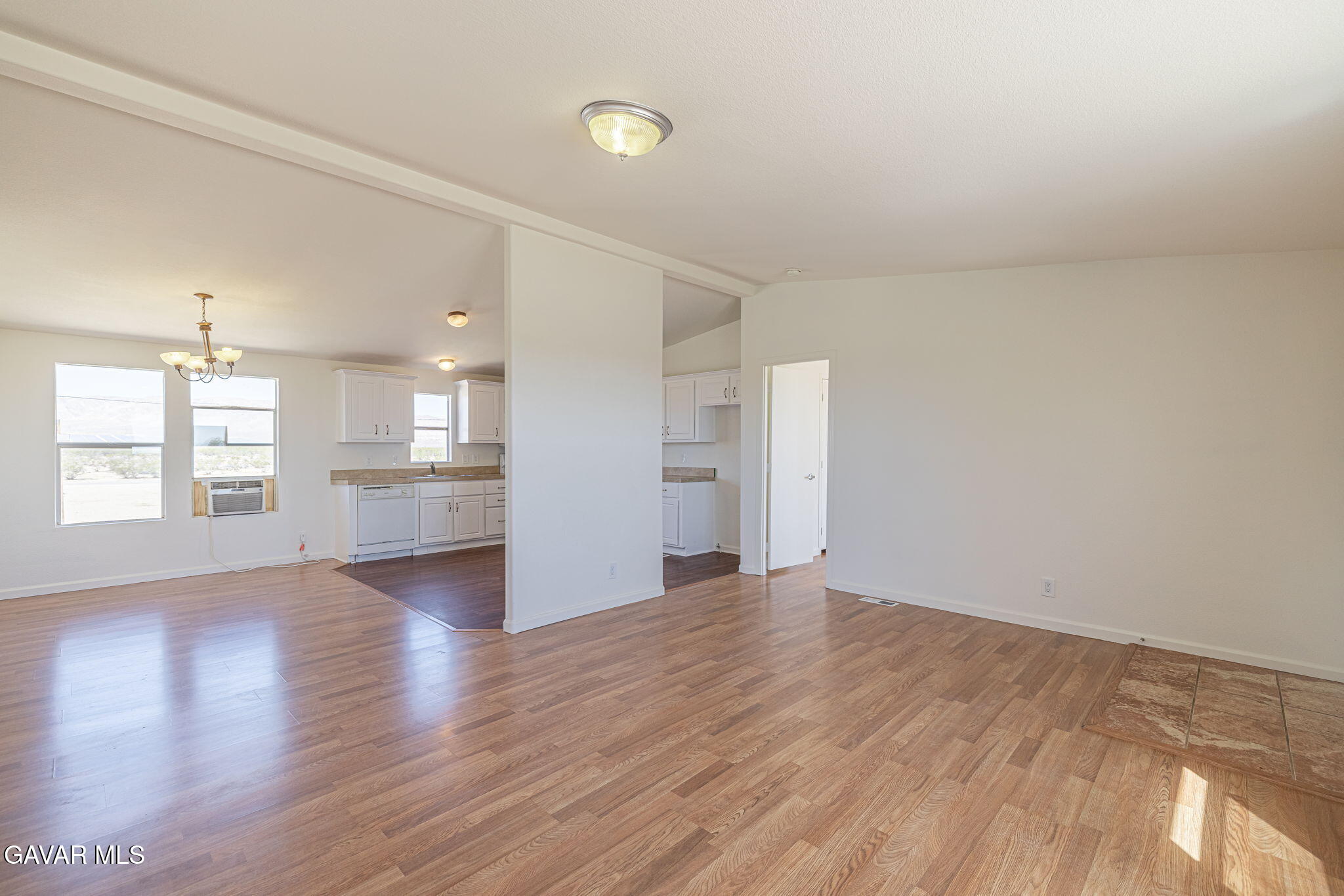 26321 Olanche Street Mojave, CA 93501 - Photo 8 of 40 an empty room with wooden floor kitchen view and windows