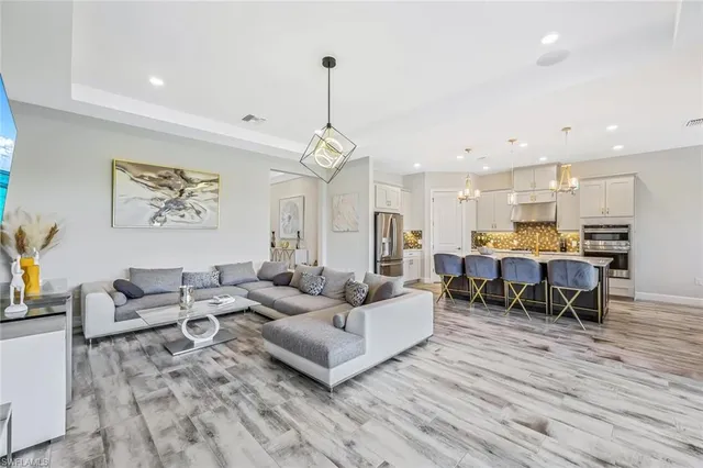 a living room with furniture kitchen view and a wooden floor