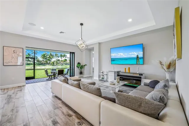 a living room with furniture floor to ceiling window and a flat screen tv