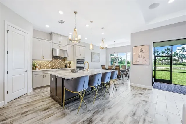 a kitchen with kitchen island granite countertop a table chairs sink and cabinets