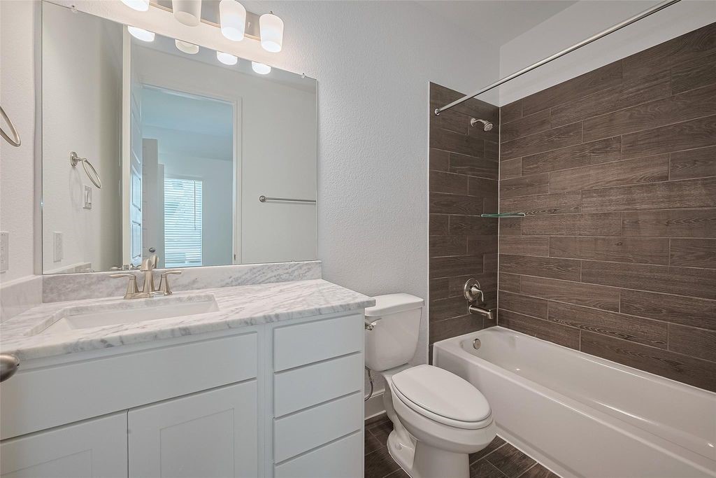 1051 Comal Trail Dayton, TX 77535 - Photo 35 of 49 a bathroom with a granite countertop sink toilet mirror and bathtub