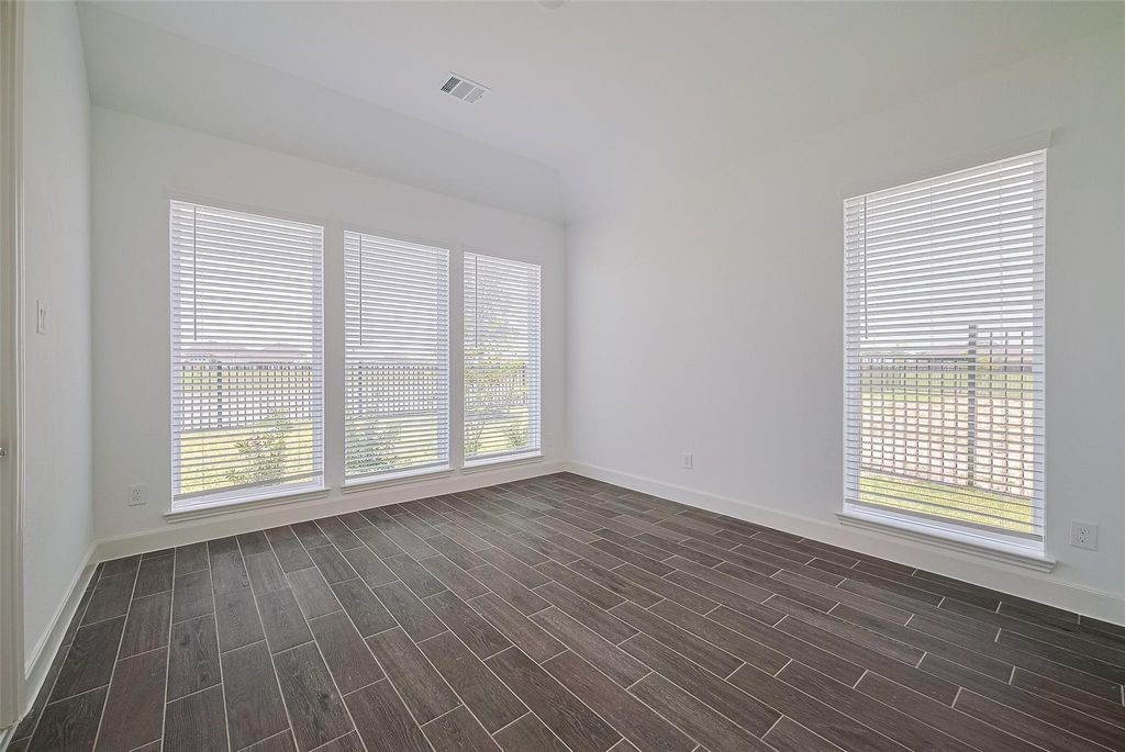 1051 Comal Trail Dayton, TX 77535 - Photo 9 of 49 an empty room with wooden floor and windows