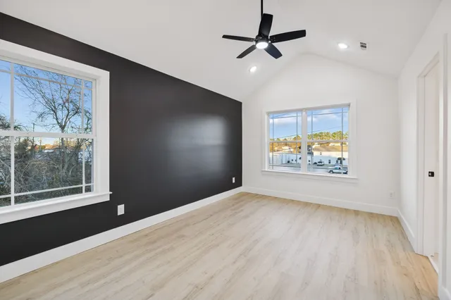 a view of an empty room with a window and wooden floor