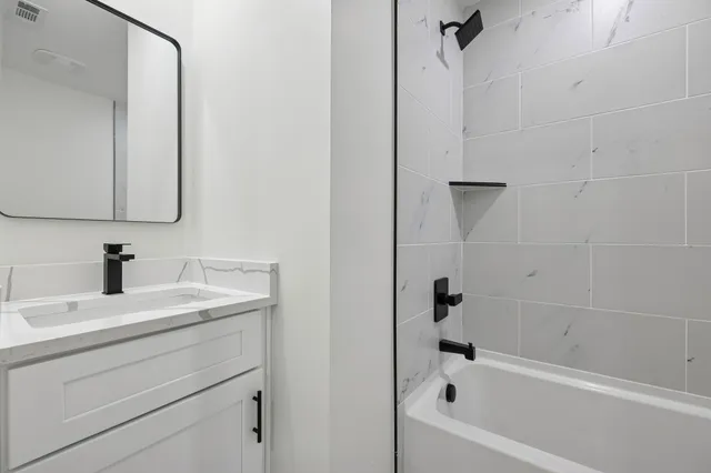 a bathroom with a bathtub sink vanity and mirror