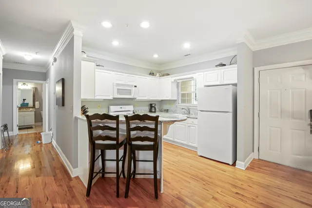 a kitchen with stainless steel appliances a refrigerator a stove a dining table and chairs with wooden floor