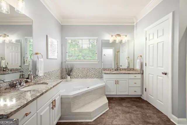 a bathroom with a granite countertop double vanity sink a mirror and a bathtub