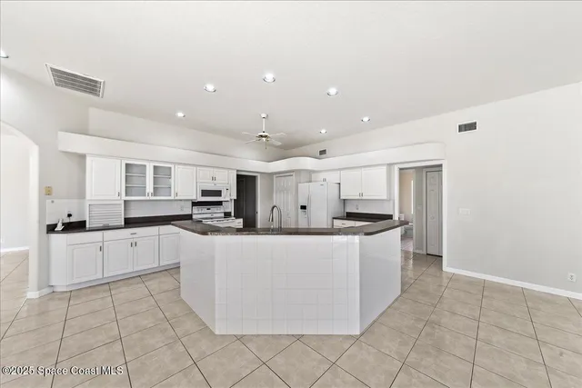 a large kitchen with stainless steel appliances a white stove top oven and white cabinets next to a window